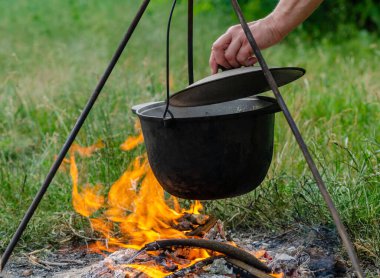 Bir tripodun üzerinde pişirilen çorba ateşte duruyor.