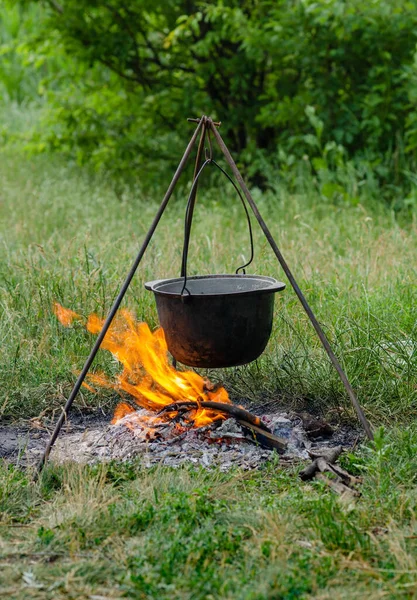 Bir tripodun üzerinde pişirilen çorba ateşte duruyor.