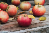 Čerstvá jablka na dřevěném stole v zahradě. Podzimní sklizeň, organická přírodní potrava. Zavřít
