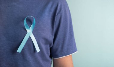 Prostat kanseri farkındalığı. Pastel arka planda açık mavi farkındalık kurdelesi olan bir adam. Kapat, pankart, kopyala alanı