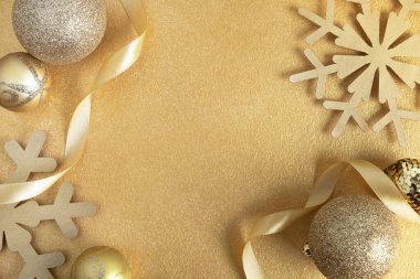 Noel, yeni yıl ya da kış kompozisyonu. Noel baloları, kar taneleri ve altın sarısı parlak arka planda şenlikli süslemeler. Üst görünüm, düz görünüm, kopyalama alanı