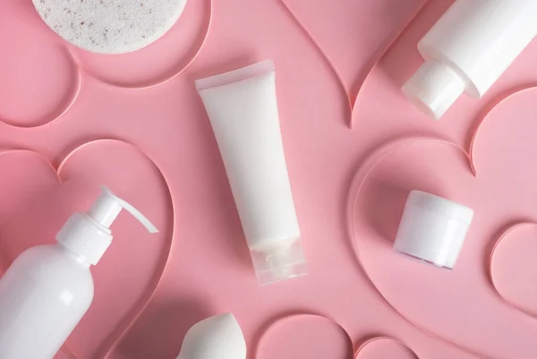 Cosmetic products with hearts festive decor on pastel pink background. Body treatment, skincare. Concept of sale, gifts on Valentines day or mother day. Top view, flat lay