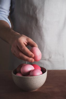 Paskalya konseptine hazırlanıyorum. Ev mutfağında paskalya yumurtaları masanın üzerine elle boyanmış bir adam. Dikey
