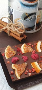 Ahududu ve portakallı el yapımı çikolata. Tarçın çubukları ve masada bir kavanoz kahve. Çikolata. Tatlı tatlı.