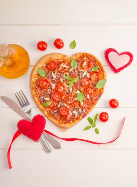 Beyaz ahşap arka planda kalpleri olan kalp şeklinde pizza Sevgililer Günü romantik akşam yemeği konsepti.
