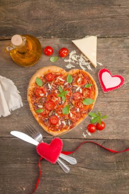 Eski ahşap arka planda kalpleri olan kalp şeklinde pizza, Sevgililer Günü için romantik akşam yemeği konsepti.
