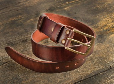 Eski bir ahşap arka planda kahverengi erkek deri pantolon kemeri..