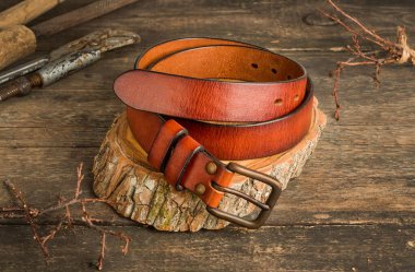 Eski bir ahşap arka planda kahverengi turuncu renkte erkek deri pantolon kemeri..