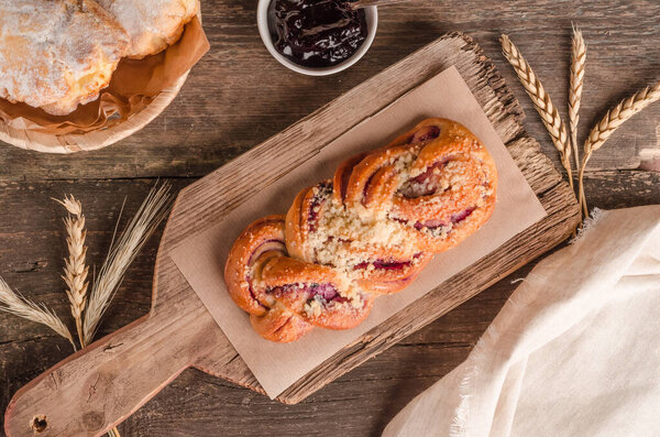 Fresh baked goods - delicious wicker bun with filling on wooden background