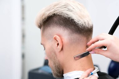 Jilet gibi keskin. Berber salonundaki sarışın genç adamın saç kesimi, erkekler ve oğlanlar için berber dükkanı konsepti