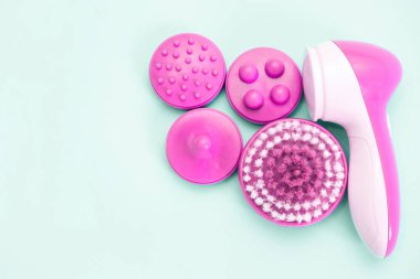 Bağlı yüz masajcısı. Yüz bakımı, turkuaz arka planda.