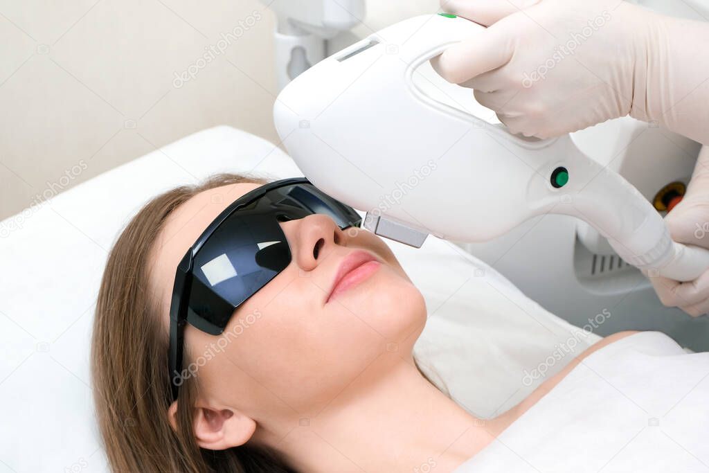Laser hair removal of the mustache and chin of a young beautiful woman. Depilation on the face. Device for laser hair removal.