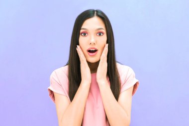 Güzel, genç, esmer kadın şaşırdı. Sürprizin ifadesi. mor izole arkaplanda