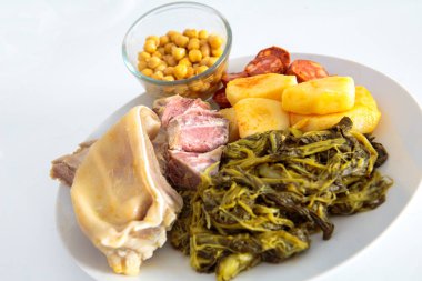 Kulak, lacon, kaburga, patates, şalgam ve nohut karışımından oluşan tipik bir Galiçya güvecinin malzemeleriyle dolu bir tabak.