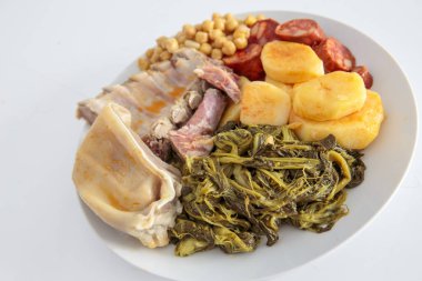 Kulak, lacon, kaburga, patates, şalgam ve nohut karışımından oluşan tipik bir Galiçya güvecinin malzemeleriyle dolu bir tabak.