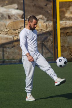 Genç erkek futbolcu futbol sahasında top çeviriyor.