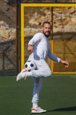 Genç erkek futbolcu futbol sahasında top çeviriyor.