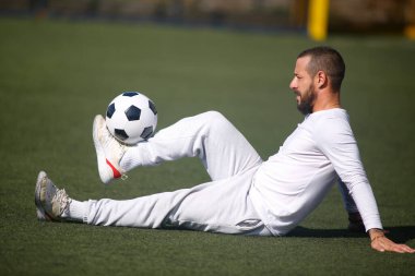 Genç erkek futbolcu futbol sahasında top çeviriyor.