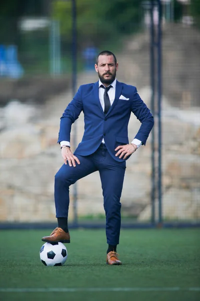 Avrupa Futbol Şampiyonası konsepti. İş adamı, futbol sahasında ayağında topla poz veriyor.