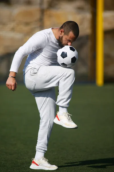 年轻的男足队员在足球场上跳着球 — 图库照片