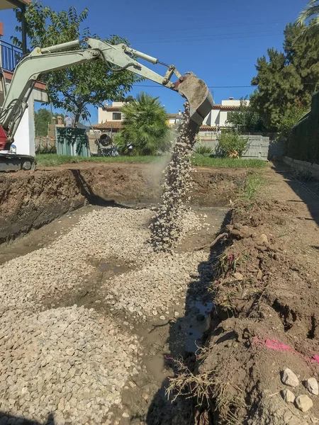Kazı makinası bir kazının altına ezilme katmanı koyar