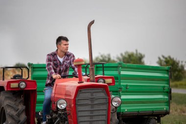 Yaz sonlarında kameraya gülümseyen çekici bir adam. Yakışıklı çiftçi hasattan sonra traktör kullanıyor..
