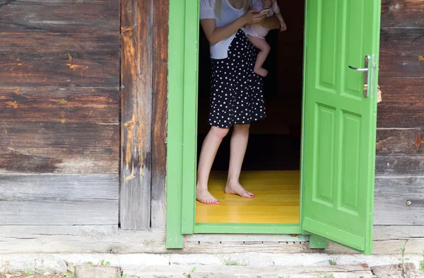 Frau mit Baby vor offener Tür — Stockfoto