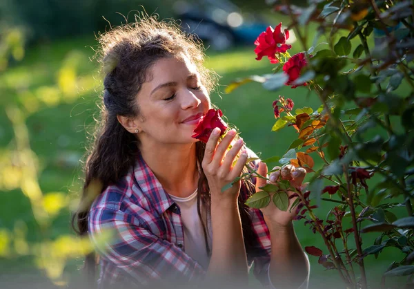 Όμορφη Νεαρή Γυναίκα Μυρίζει Κόκκινα Τριαντάφυλλα Στον Κήπο Απολαμβάνοντας Τον — Φωτογραφία Αρχείου