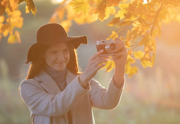 秋の時間に公園で古いアナログカメラで写真を撮る赤毛の女の子の肖像画 — ストック写真
