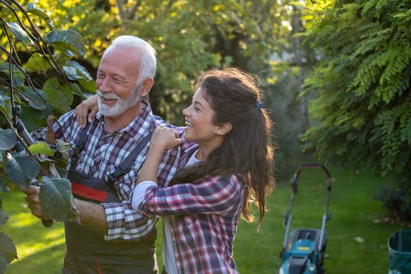 Senior Man Pruning Branches Tree While Pretty Daughter Hugging Him — Stock Photo, Image