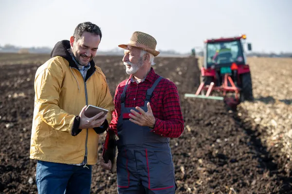 Δύο Αγρότες Στέκονται Στο Πεδίο Φθινόπωρο Κρατώντας Tablet Και Μιλώντας — Φωτογραφία Αρχείου
