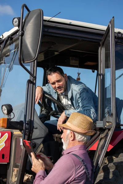 Зрелый Водитель Сидящий Тракторе Разговаривающий Старшим Фермером Рядом Машиной Поле — стоковое фото