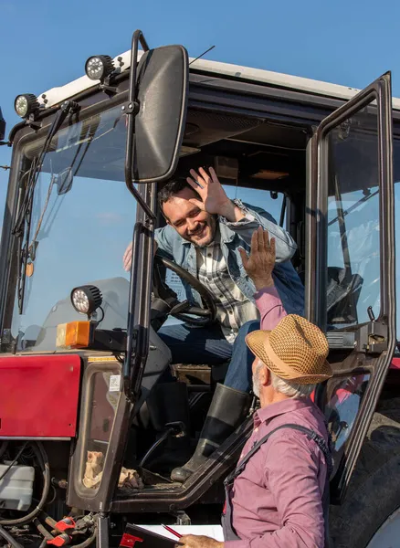 トラクターに座ってフィールドに車の横にあるシニア農家と話を成熟したドライバー — ストック写真