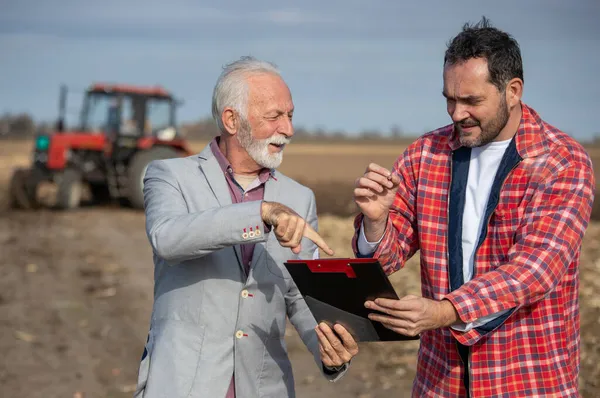Старший Бізнесмен Показує Дорослому Фермеру Підписати Контракт Полі Перед Трактором — стокове фото