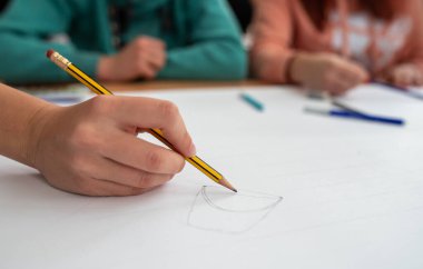 Close up of student's hand drawing and writing presentation on team building workshop