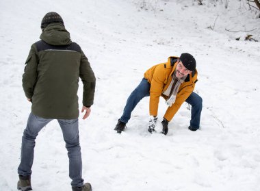 Father and son playing snowball fight on park on cold winter day