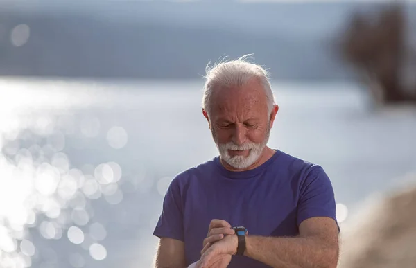 Senior Man Checking Information Smart Watch Jogging River — Stock fotografie
