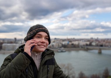 Gülümseyen bir gencin portresi oturuyor ve telefonda konuşuyor.