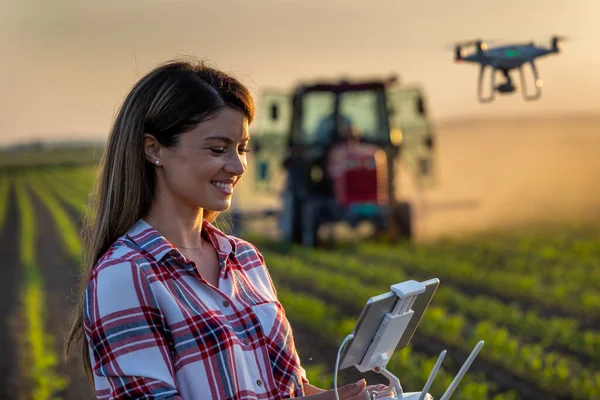 Όμορφη Νεαρή Αγρότισσα Γυναίκα Οδήγηση Drone Τηλεχειριστήριο Μπροστά Από Τρακτέρ — Φωτογραφία Αρχείου