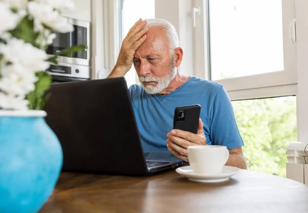 Upprörd Senior Man Sitter Vid Matbordet Hemma Håller Mobiltelefon Och — Stockfoto