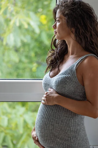 Vacker Gravid Kvinna Klänning Står Bredvid Fönstret Och Tittar Med — Stockfoto