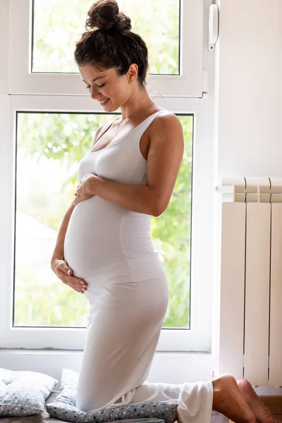 窓の前で腹に手を握って白い手に美しい妊婦 成長期と赤ん坊の愛の概念 — ストック写真