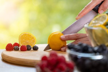 Kadın elinin mutfak bıçağıyla limon kesme, sağlıklı içecek ya da salata hazırlama.