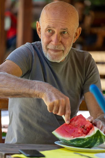 Senior Άνθρωπος Τρώει Φρέσκο Ώριμο Καρπούζι Ξύλινο Τραπέζι Στη Βεράντα — Φωτογραφία Αρχείου