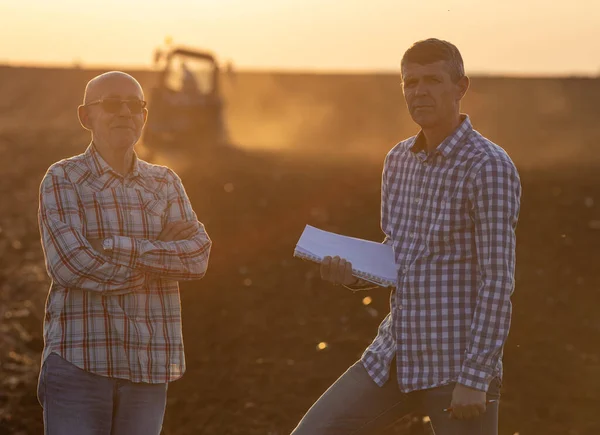 Retrato Dois Agricultores Seniores Campo Pôr Sol Com Trator Trabalhando — Fotografia de Stock