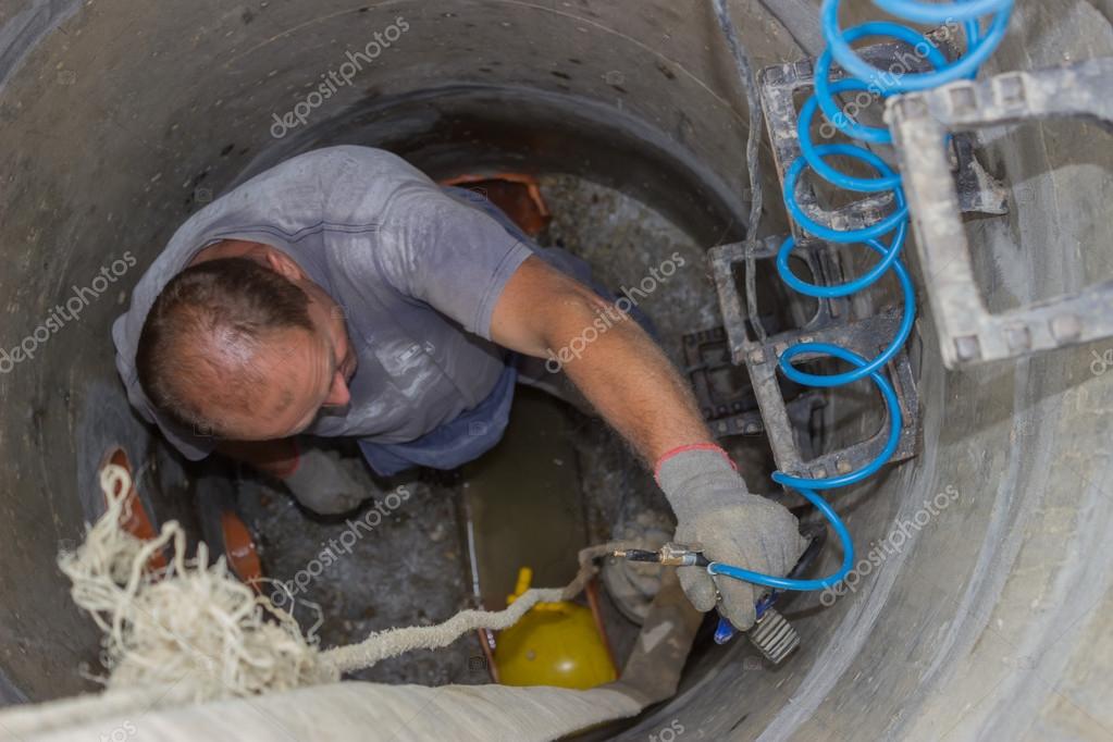 Worker inside a manhole working in stock