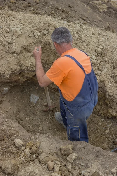 Worker with a shovel looking for lost manhole after working exca — Stock Photo, Image