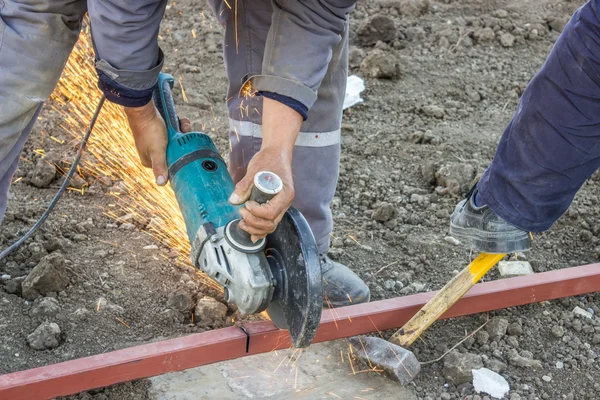 Close up of metal worker using angle grinder to cut metal bar — Stock Photo, Image