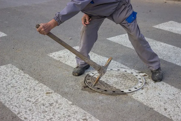 Utilitários trabalhador move a tampa do bueiro — Fotografia de Stock