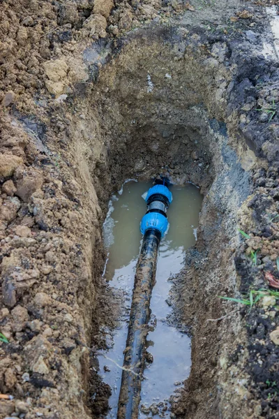 Broken pvc pipe in trench leaks water — Stock Photo, Image